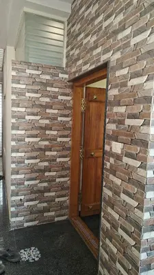 a brick wall next to a door in a room at Gamani in Mysore