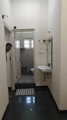 a man standing in a bathroom with a sink at Gamani in Mysore