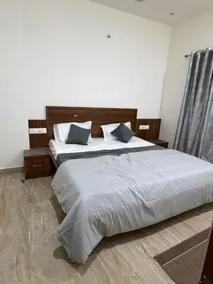 a bedroom with a bed with white sheets and blue pillows at The Residence 267 Home Stay in Mysore