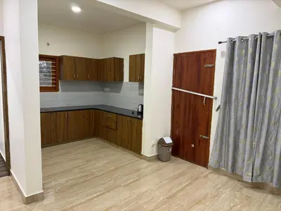 a kitchen with wooden cabinets and a shower curtain at The Residence 267 Home Stay in Mysore