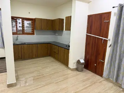 an empty kitchen with wooden cabinets and a window at The Residence 267 Home Stay in Mysore