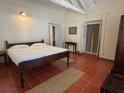 a bedroom with a bed and a red tile floor at Ellem House in Kotagiri
