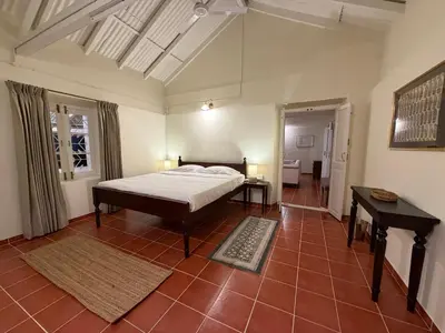 a bedroom with a bed and a table in it at Ellem House in Kotagiri