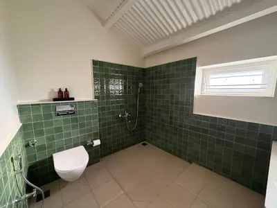 a green tiled bathroom with a toilet and a window at Ellem House in Kotagiri