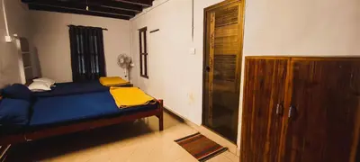 a bedroom with a blue bed and a wooden cabinet at Wildora Junglevilla Wayanad in Chekadi