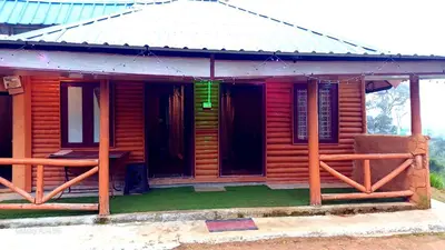 a wooden house with a porch and a fence at Mud bees resort in Kanthalloor