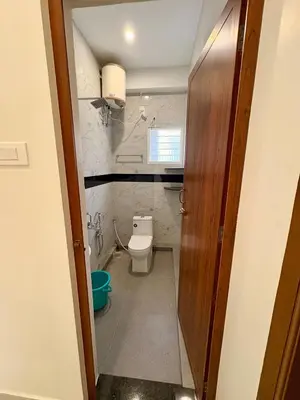 a small bathroom with a toilet and a door at Nexusliving in Coimbatore