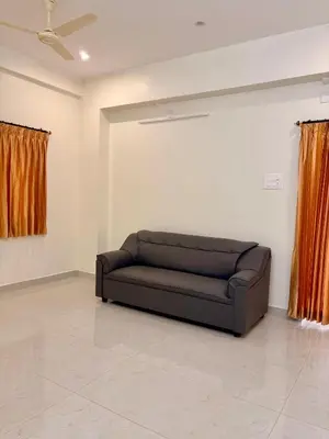 a black couch in a room with orange curtains at Nexusliving in Coimbatore