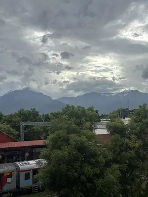 a train on a track with mountains in the background at House of KRM - Nilgiris Outlook in Kāramadai