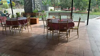 a patio with two tables and chairs and a pond at Pochans Zen in Thattakād
