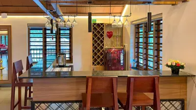 a kitchen with a bar with chairs and a counter top at Pochans Zen in Thattakād
