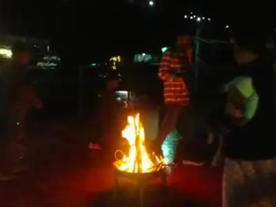 a group of people standing around a fire at night at Nakshatra Home Stay in Vattavada