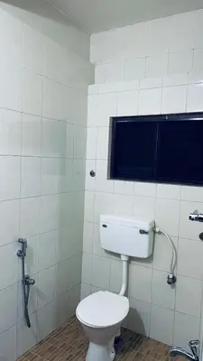 a bathroom with a white toilet and a window at Saravana tourist home in Kozhikode