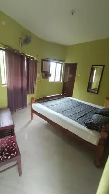 a large bed in a room with green walls at Silver Rock Cottage Valparai in Vālpārai