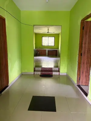 a green room with a bed and a window at Silver Rock Cottage Valparai in Vālpārai