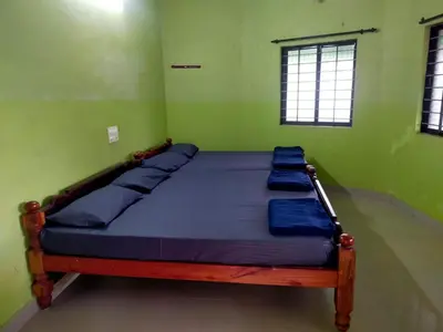 a bed in a green room with blue pillows on it at Silver Rock Cottage Valparai in Vālpārai