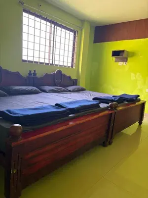 a large wooden bed in a room with yellow walls at Silver Rock Cottage Valparai in Vālpārai
