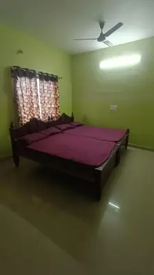 a large bed in a green room with a window at Silver Rock Cottage Valparai in Vālpārai