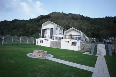 a large white house with a hill in the background at Jacaranda Home Stay in Kotagiri