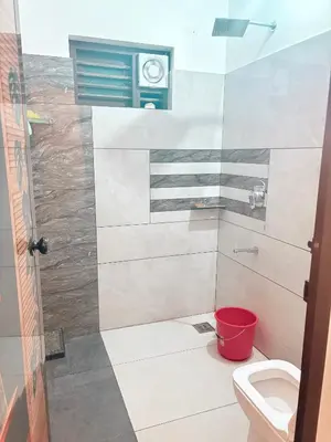 a bathroom with a toilet and a red bucket at Tanis serenity in Meenangadi