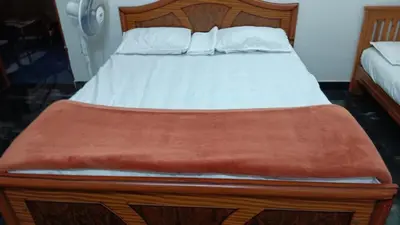 a bed with a wooden frame and white sheets and pillows at PK Homestay in Coimbatore