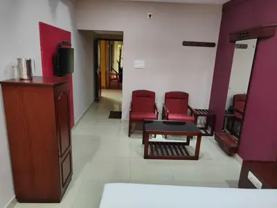 a waiting room with red chairs and a table at Chandragiri INN in Kalpetta