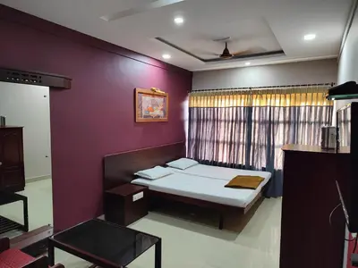 a bedroom with a bed and a purple wall at Chandragiri INN in Kalpetta