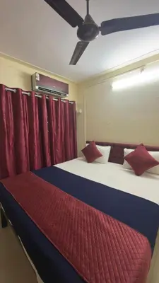 a bedroom with two beds with red curtains at Roshan's Welcome Home Stay in Mysore