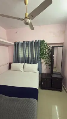 a bedroom with a bed and a mirror and a ceiling fan at Roshan's Welcome Home Stay in Mysore