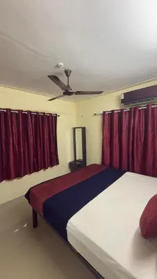 a bedroom with a large bed with red curtains at Roshan's Welcome Home Stay in Mysore