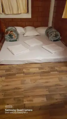 a large white bed with pillows on a wooden floor at Stay with Lakeview Ponnampet in Ponnampet
