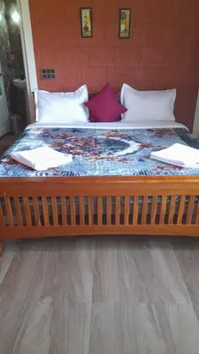 a large bed with a wooden foot board at Stay with Lakeview Ponnampet in Ponnampet