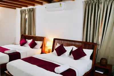 two beds in a hotel room with red and white pillows at 50 Fables Vintage Kerala Pool Home in Pulpally