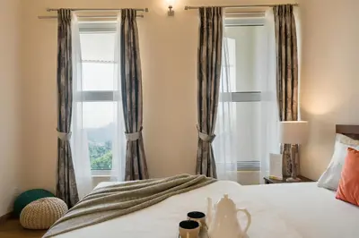 a bedroom with a bed with curtains and a window at SaffronStays Valleyfall in Kotagiri