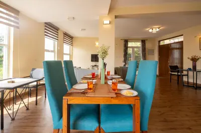 a dining room with a table and blue chairs at SaffronStays Valleyfall in Kotagiri