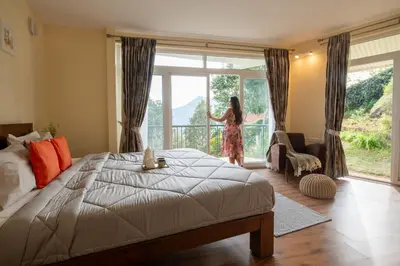 a woman looking out the window of a bedroom at SaffronStays Valleyfall in Kotagiri