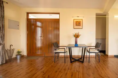 a room with a table and chairs and a wooden door at SaffronStays Valleyfall in Kotagiri