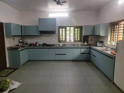 a kitchen with blue cabinets and a white tile floor at AANMEEZ Homestay in Kuthuparamba