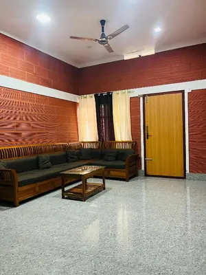 a living room with couches and a brick wall at Spillway private pool villa in Meenangadi