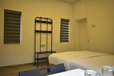 a room with two beds and a table and windows at Rays Of Bliss Boutique Resort in Mananthavady