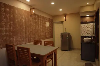 a kitchen with a table and a refrigerator at Vista Chembra Service Apartment 20A in Meppādi