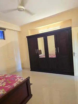 a bedroom with a bed and a cabinet with mirrors at The Western Castle Apartment - 2BHK Apartment in Kannur