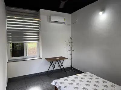 a room with a bed and a table and a window at Spice garden farm stay in Kodali