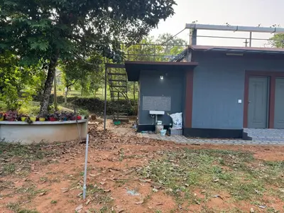 a blue building with a tree in front of it at Spice garden farm stay in Kodali