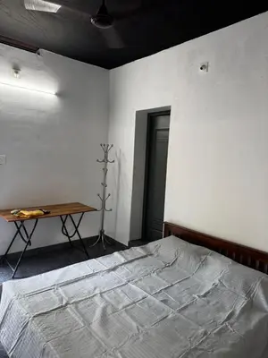 a bedroom with a bed and a table in it at Spice garden farm stay in Kodali
