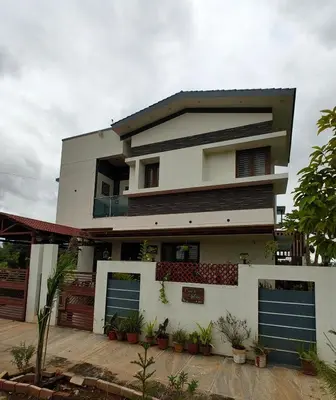 a white house with blue garage doors and plants at shalom 3bhk in Mysore