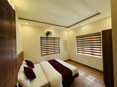 a bedroom with a bed and two windows at Honeymoon Holidays in Vythiri
