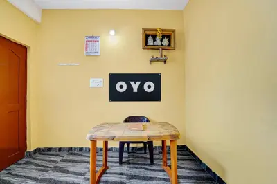 a table in a room with a sign on a wall at Hotel O Nimishamba Residency in Mysore