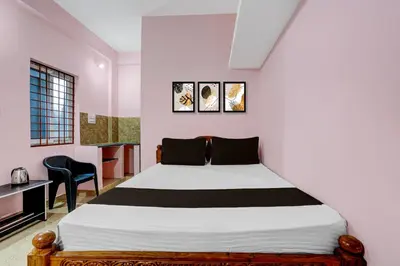 a bedroom with a bed and a desk and a window at Hotel O Nimishamba Residency in Mysore
