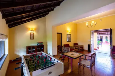 a living room with a foosball table and a room with a dining area at amã Stays & Trails - Cottabetta Bungalow, Coorg in Gonikoppal